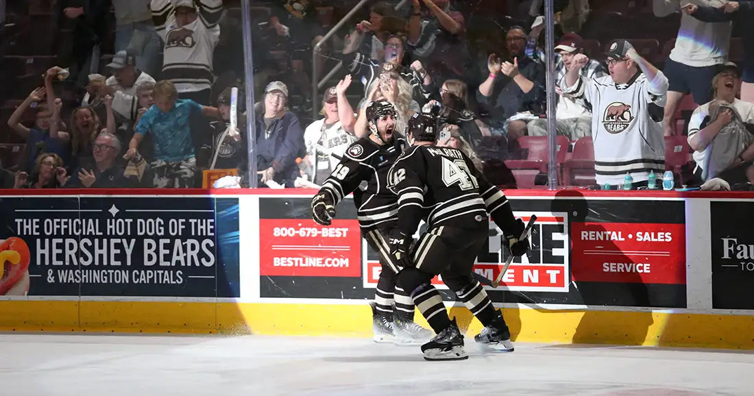 Two Bears players celebrating together while crowd cheers on from stands.